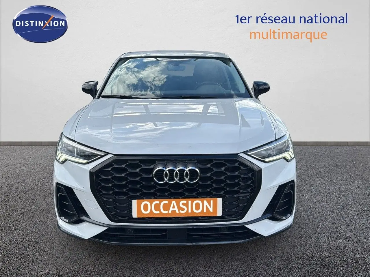 Vue frontale d'un Audi Q3 Sportback blanc 2021 avec calandre noire et phares LED allumés.