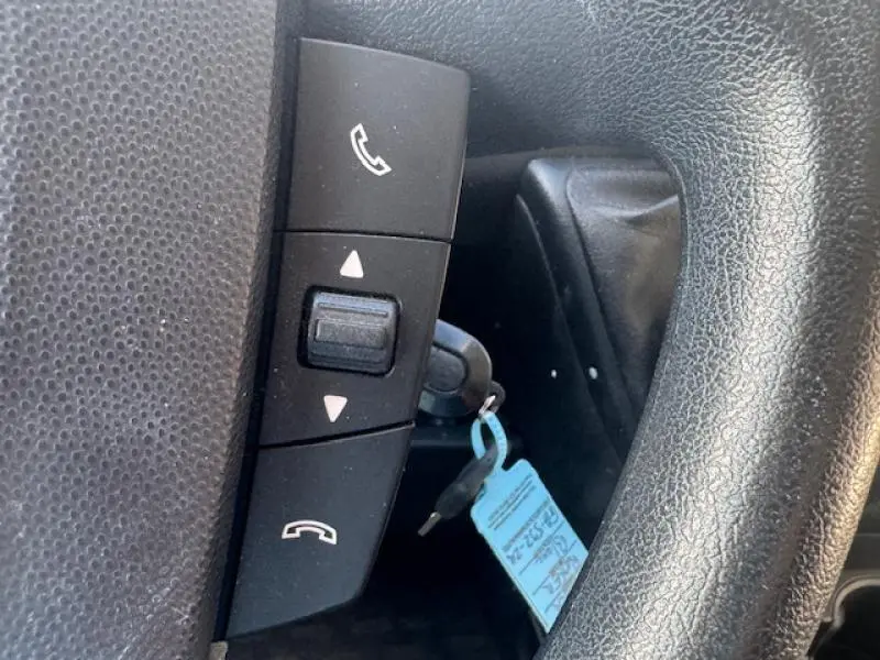 Gros plan sur les commandes Bluetooth au volant noir du Peugeot Boxer Fourgon blanc Banquise 2018.