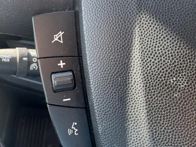 Gros plan sur les commandes au volant du Peugeot Boxer Fourgon blanc Banquise, avec boutons de volume et fonction mains-libres.