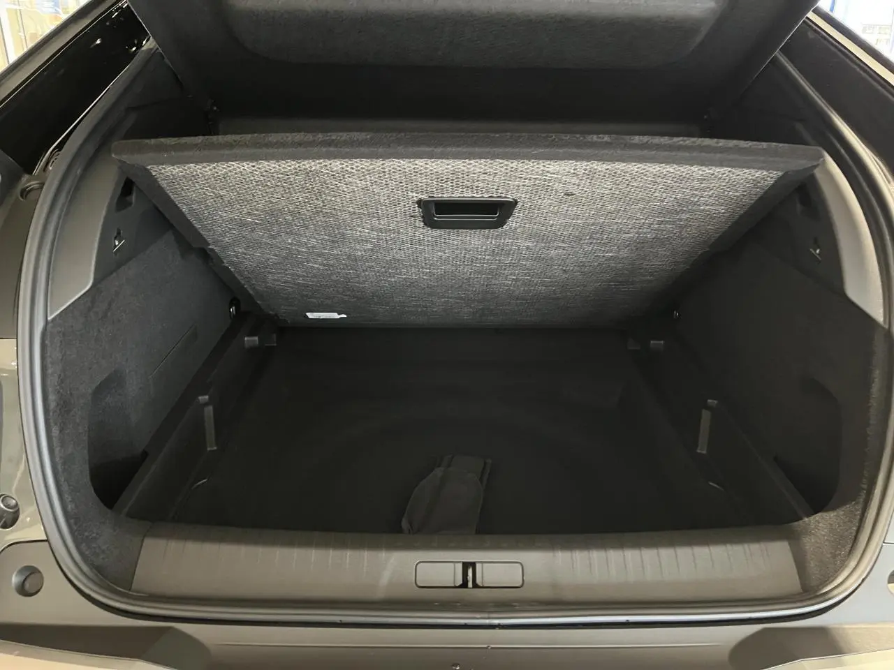 Vue arrière du coffre ouvert du Peugeot 3008 gris titanium, montrant le compartiment de rangement sous plancher.