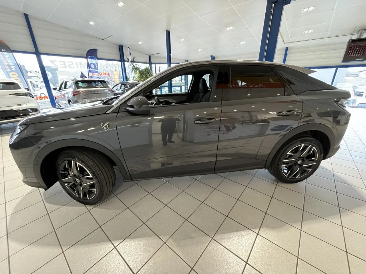 Vue de profil côté gauche d’un Peugeot 3008 gris titanium avec jantes alliage noires et badge GT visible sur l’aile avant.