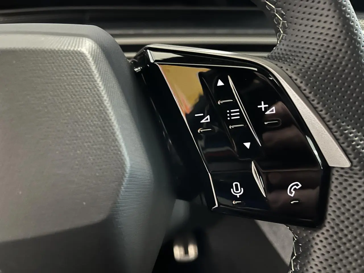Gros plan sur commandes tactiles noires à droite du volant perforé du Peugeot 3008 gris titanium 2025.