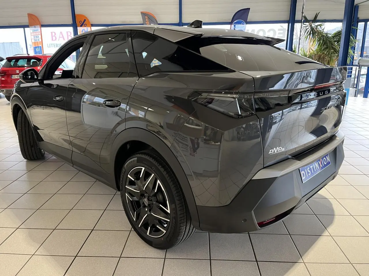 Vue 3/4 arrière droite du Peugeot 3008 gris titanium avec jantes alliage 19'' et bandeau noir laqué entre feux arrière.