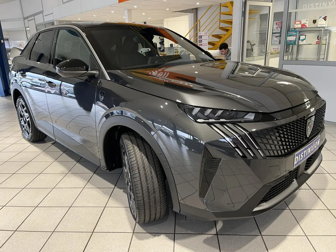 Peugeot 3008 gris titanium en 3/4 avant droit, avec calandre noire et feux LED griffés distinctifs.