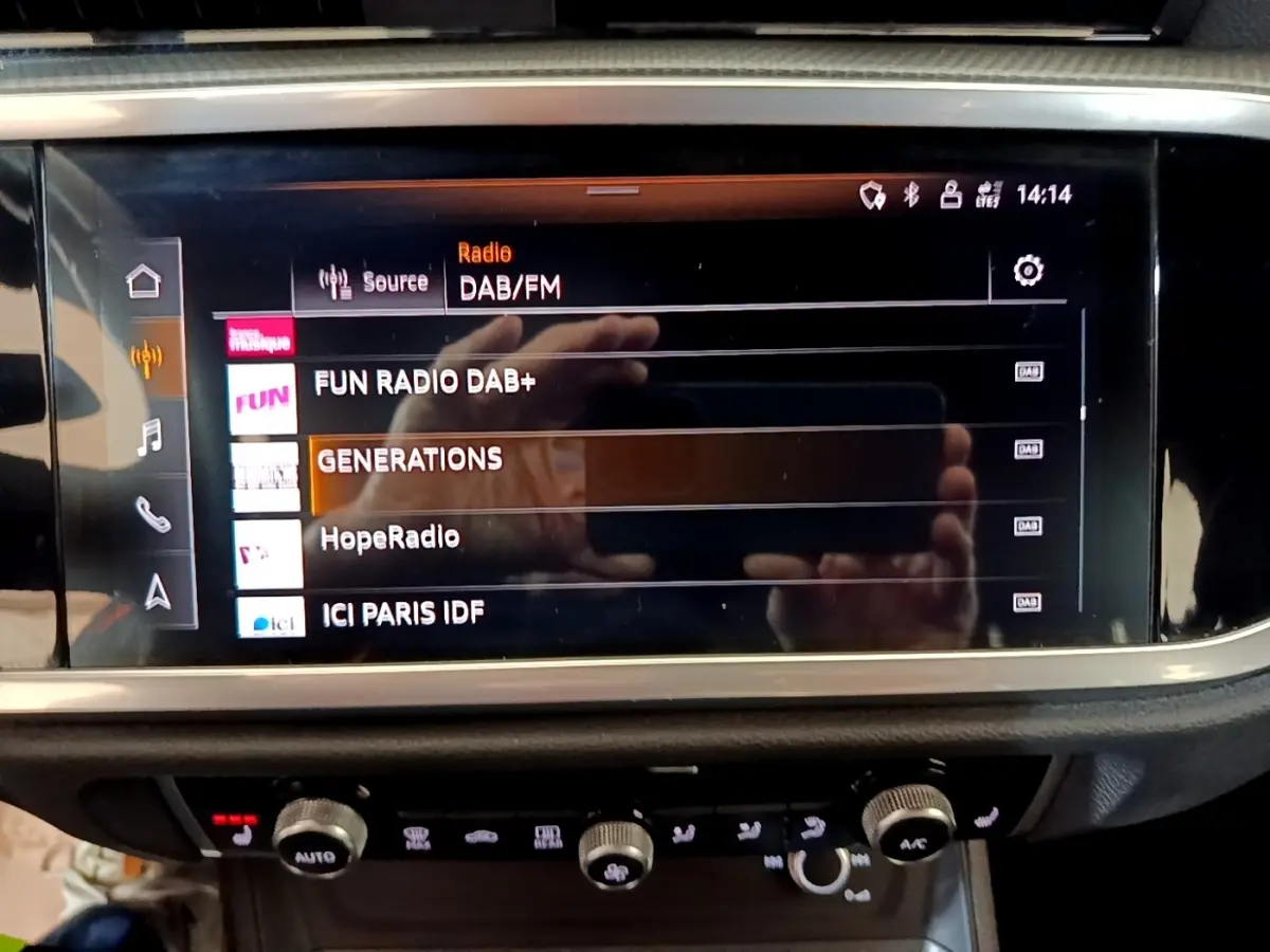 Écran tactile central de l’Audi Q3 35 TFSI S Line 2022 affichant les stations radio DAB/FM en intérieur noir.