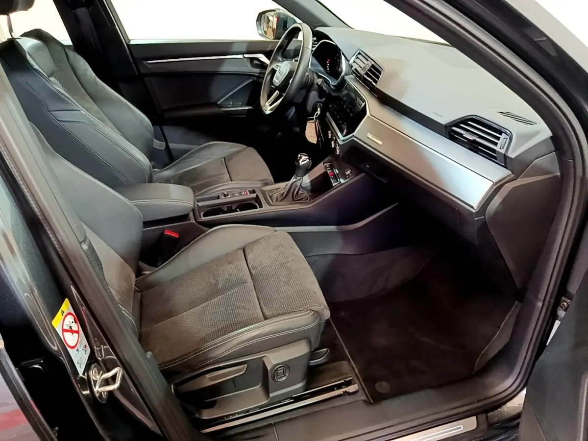 Vue intérieure côté conducteur de l’Audi Q3 gris foncé 35 TFSI S Line avec tableau de bord moderne et sièges en tissu.