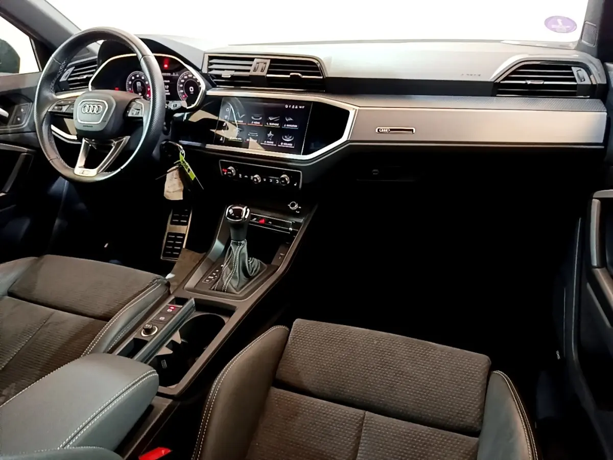 Vue intérieure côté conducteur de l'Audi Q3 35 TFSI S Line 2022 avec tableau de bord noir et écran tactile central.