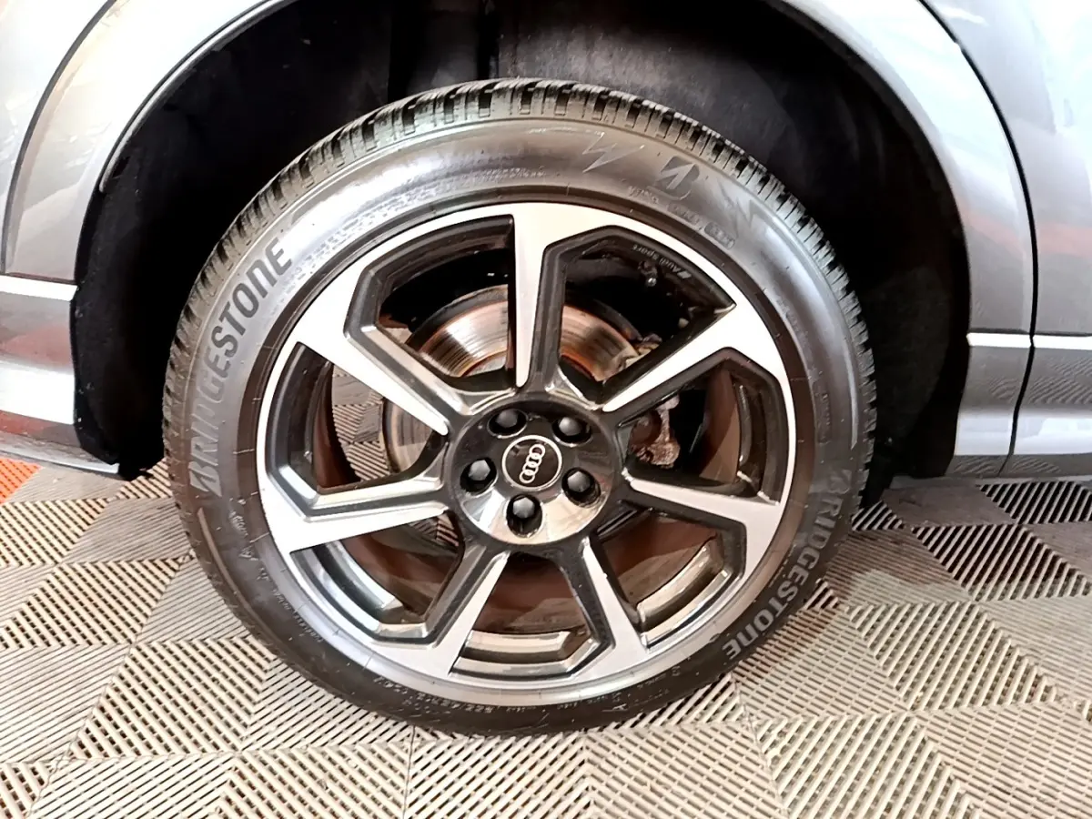 Gros plan sur la roue avant gauche de l'Audi Q3 gris foncé, avec jante alliage cinq branches et pneu Bridgestone.