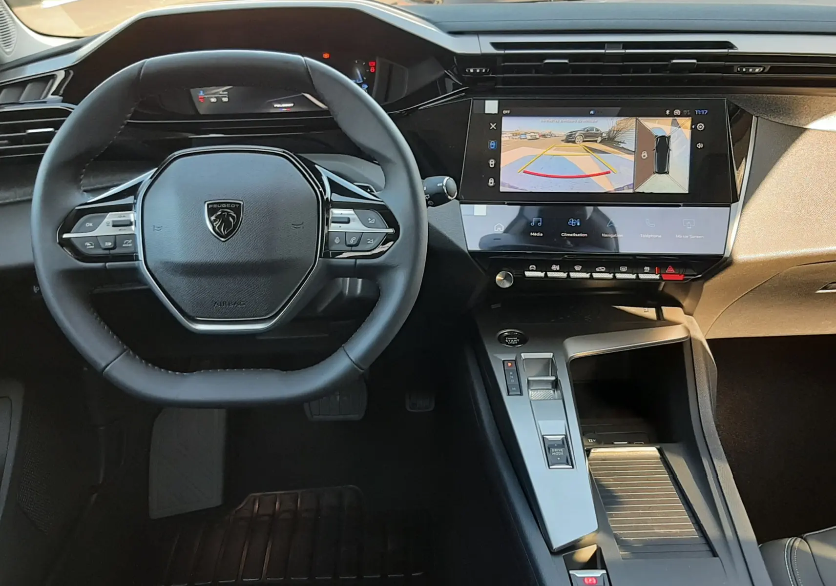 Vue intérieure centrée sur le volant et la console centrale de la Peugeot 308 2026, avec écran tactile affichant la caméra 360°.