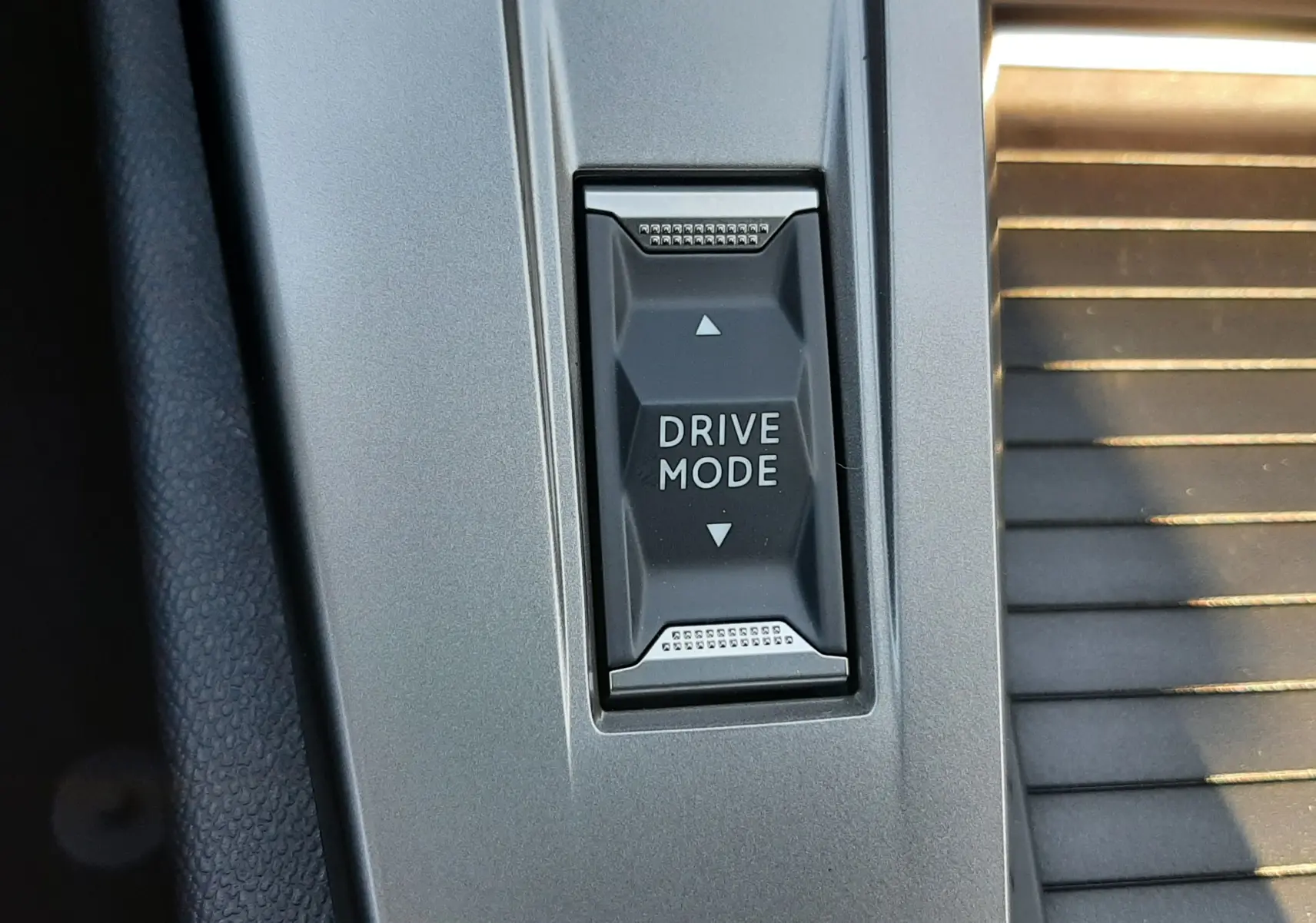 Gros plan sur le bouton Drive Mode noir intégré dans la console centrale grise du Peugeot 308 Bleu Obsession 2026.
