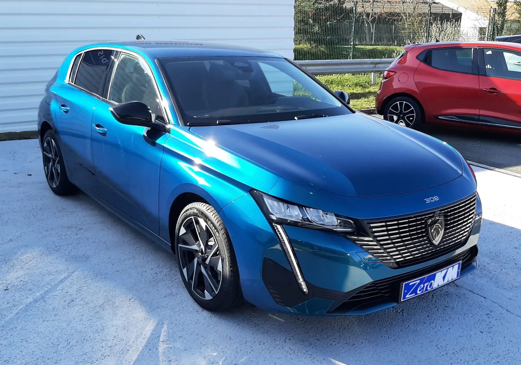 Peugeot 308 Bleu Obsession vue 3/4 avant droit, mettant en valeur sa calandre distinctive et ses jantes alliage.