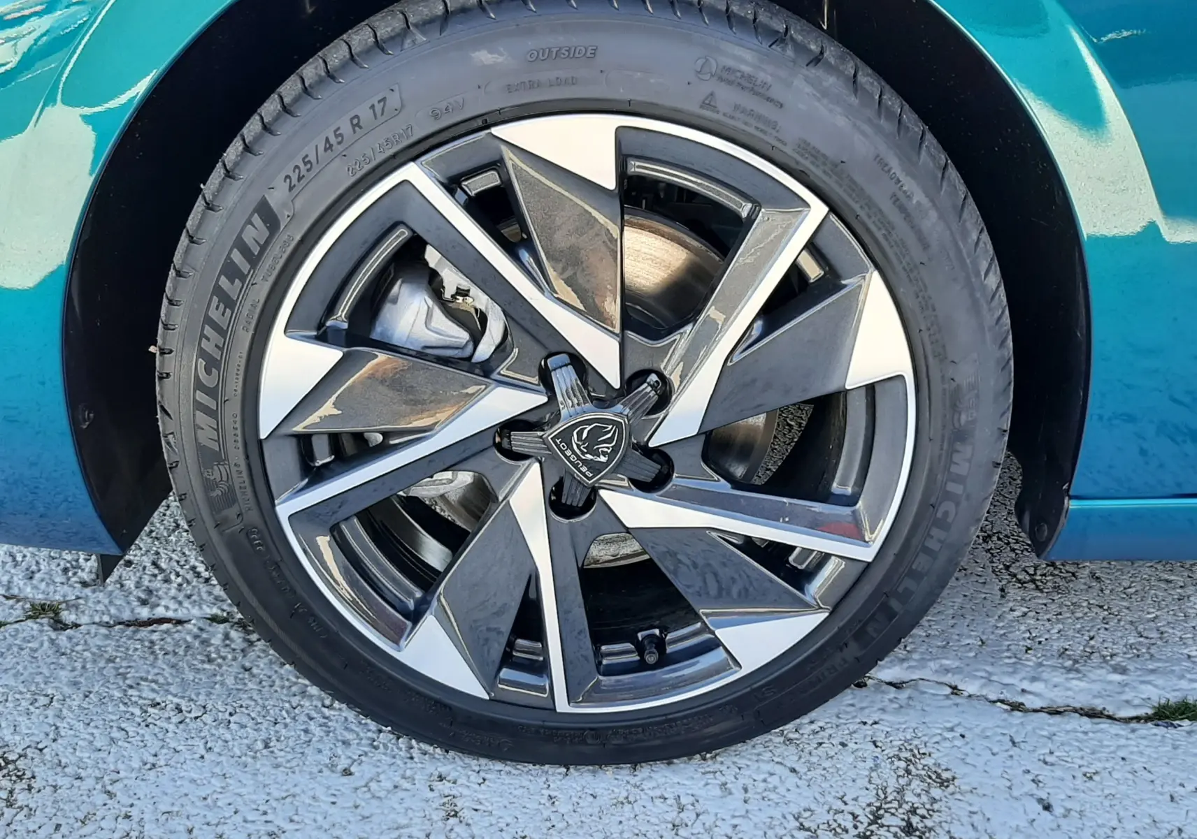 Gros plan sur la roue avant droite d'une Peugeot 308 Bleu Obsession avec jante alliage bicolore et pneu Michelin.