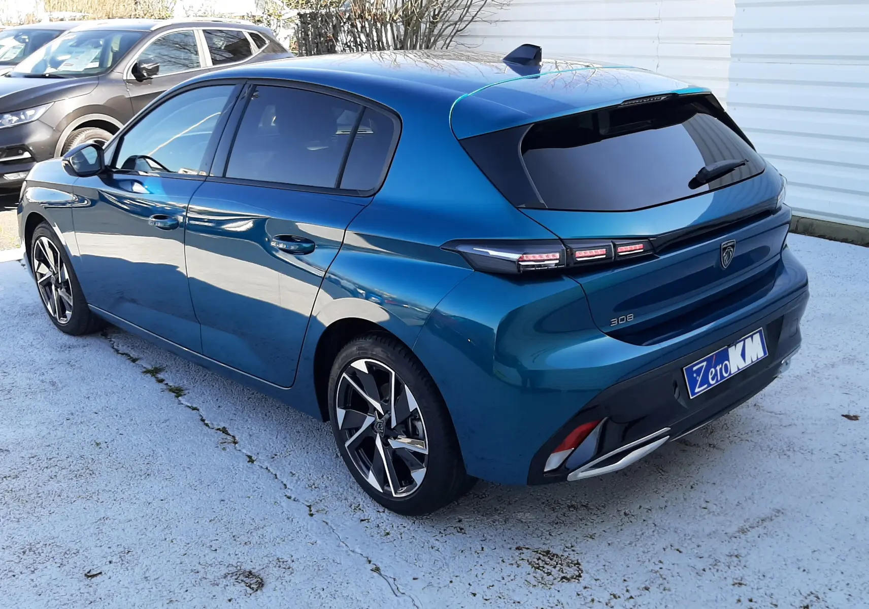 Vue 3/4 arrière droite d'une Peugeot 308 Bleu Obsession avec feux arrière distinctifs et jantes alliage bicolores.