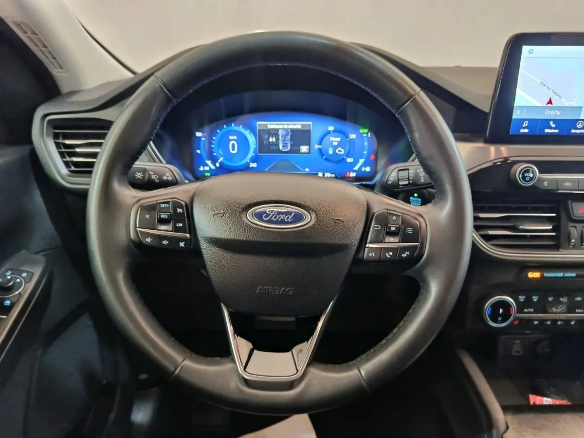 Vue intérieure centrée sur le volant cuir noir du Ford Kuga 2023 avec tableau de bord numérique et écran tactile.