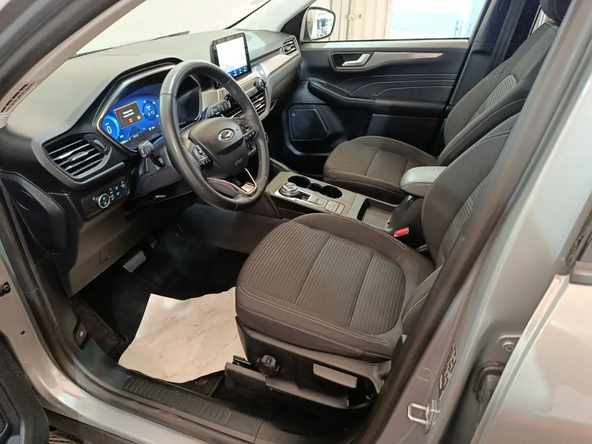 Intérieur avant droit du Ford Kuga gris foncé 2023, avec tableau de bord numérique et volant multifonctions.