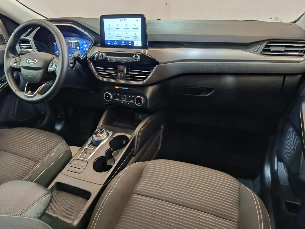 Vue intérieure avant du Ford Kuga 2023 gris foncé, avec tableau de bord digital et écran tactile central.