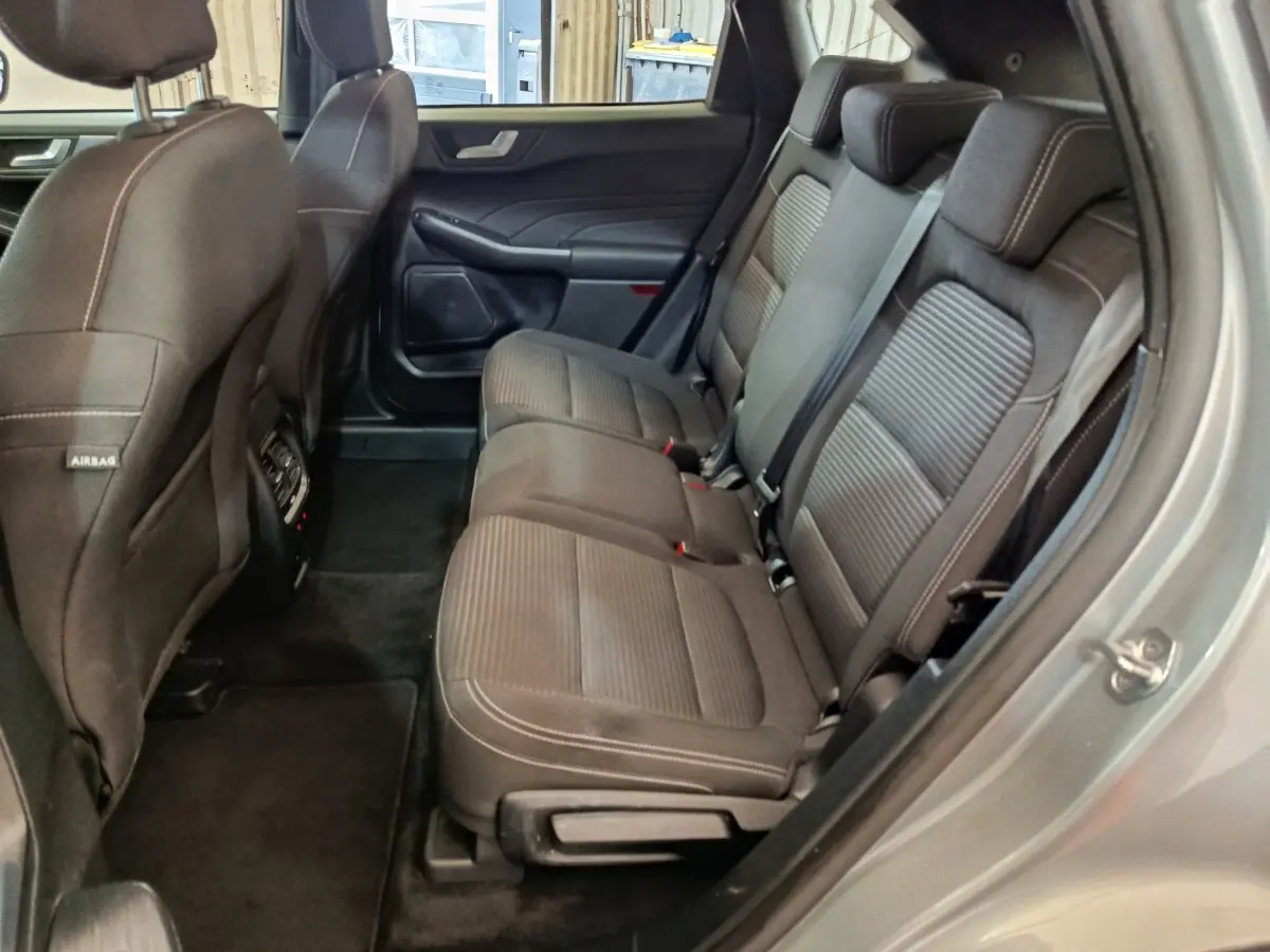 Vue intérieure côté droit montrant la banquette arrière en tissu gris foncé du Ford Kuga 2023 hybride.