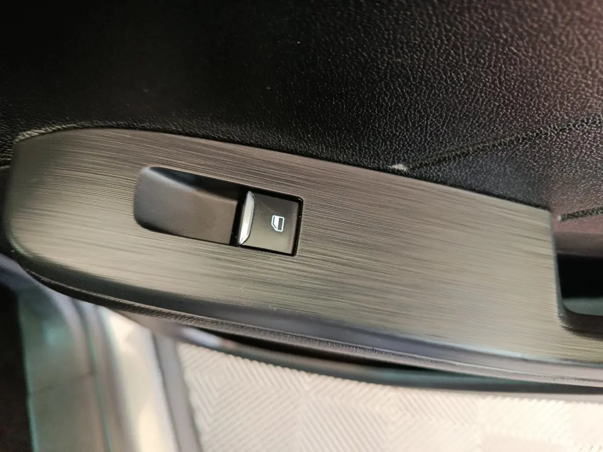 Gros plan sur le bouton de commande de la vitre électrique côté conducteur du Ford Kuga gris foncé, finition Titanium.