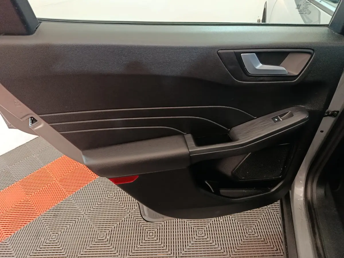 Vue rapprochée de la porte avant droite intérieure du Ford Kuga 2023, avec garniture noire et commande de vitre.