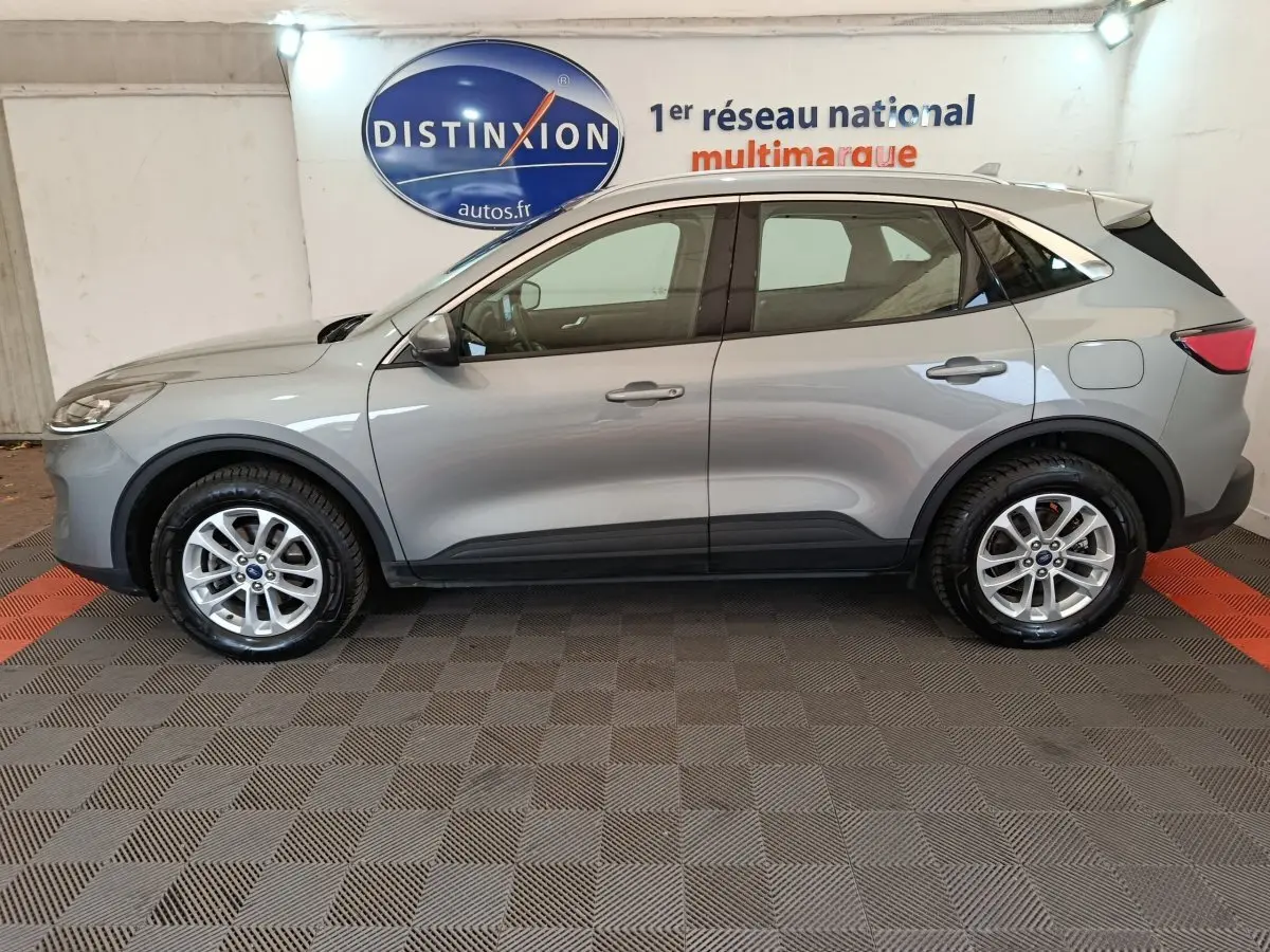 Vue de profil côté gauche d'un Ford Kuga gris foncé 2023 avec jantes alliage et barres de toit chromées.