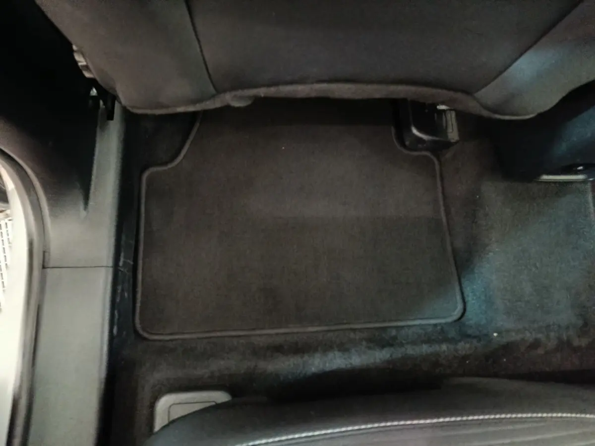 Vue intérieure du plancher arrière avec tapis noir du Ford Kuga 2023 gris foncé, côté droit sous le siège passager.