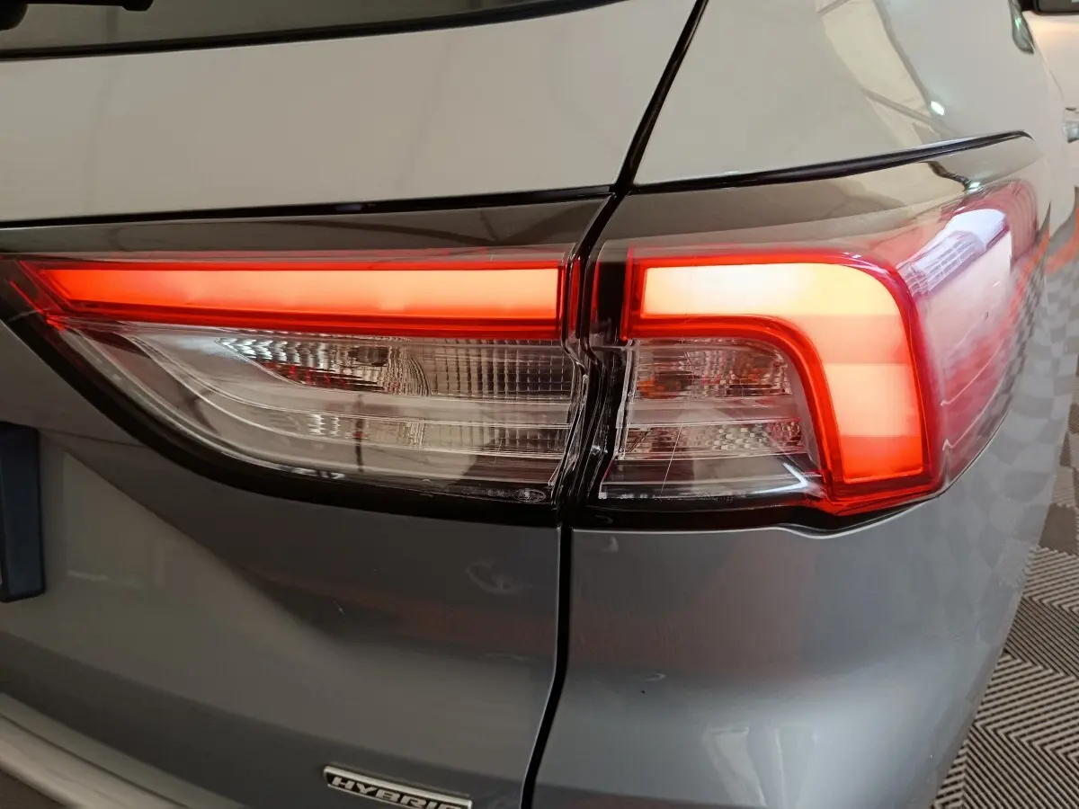 Gros plan sur le feu arrière droit allumé du Ford Kuga gris foncé hybride 2023, avec badge Hybrid visible.