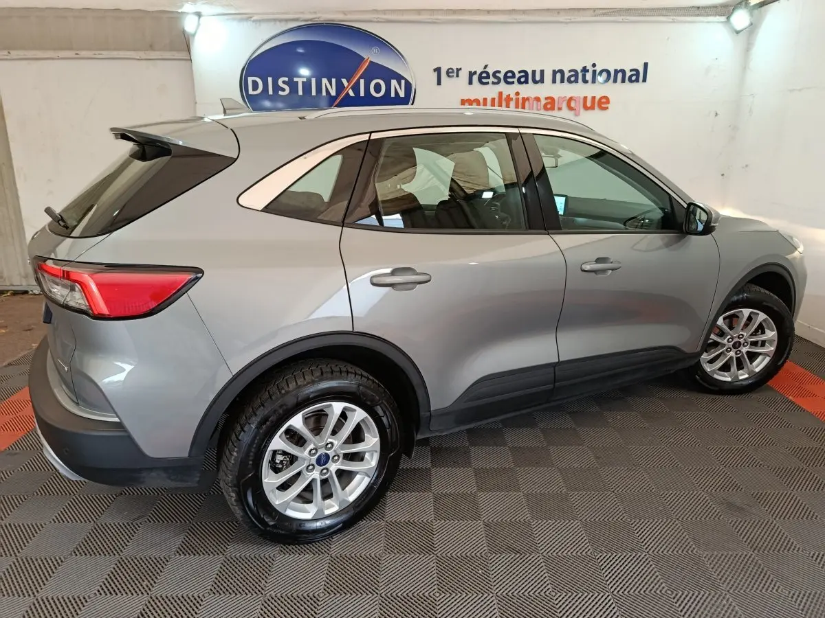 Vue latérale droite d'un Ford Kuga 2.5 Hybrid gris foncé 2023 avec jantes alliage et rails de toit chromés.
