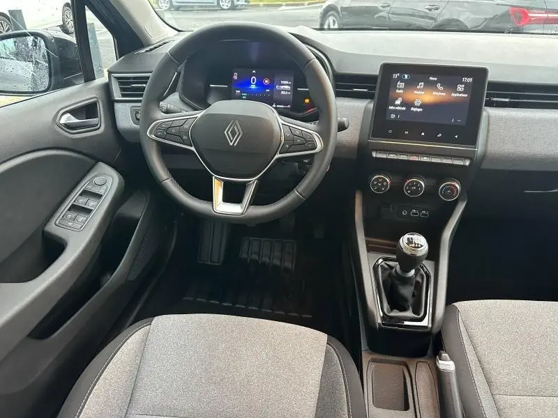 Vue intérieure avant de la Renault Clio 1.0 TCe 90ch Evolution 2025, tableau de bord gris avec écran tactile et boîte manuelle.
