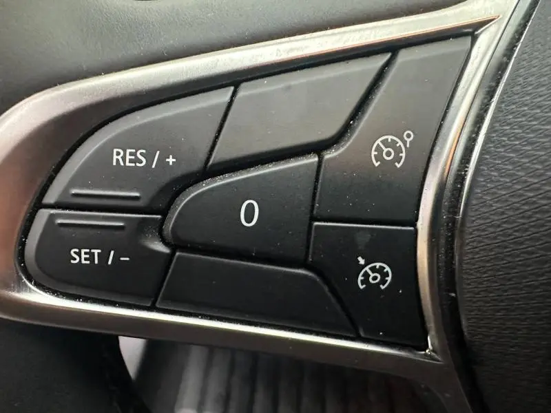 Gros plan sur les commandes noires du régulateur de vitesse au volant d'une Renault Clio 2025, finition Evolution.