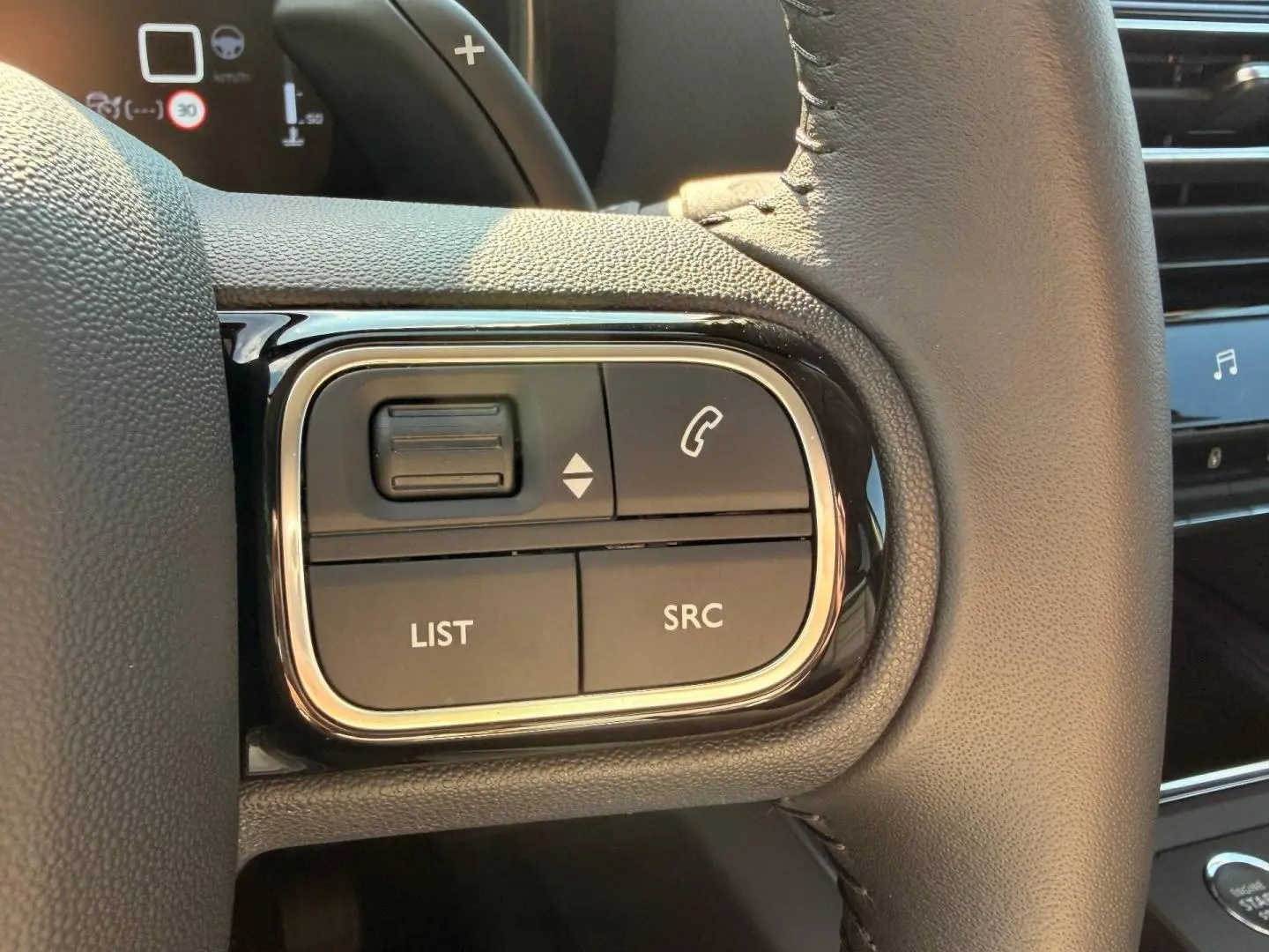 Gros plan sur les commandes gauche du volant cuir noir du Citroën C5 Aircross 2025, avec boutons SRC et LIST visibles.