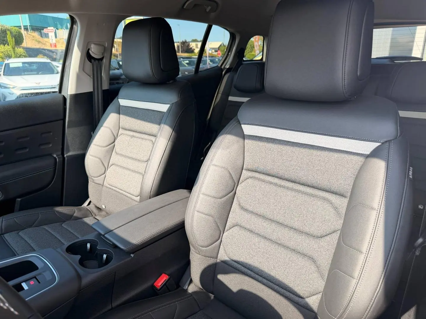 Vue intérieure rapprochée des sièges avant en tissu noir et cuir du Citroën C5 Aircross 2025, avec accoudoir central.