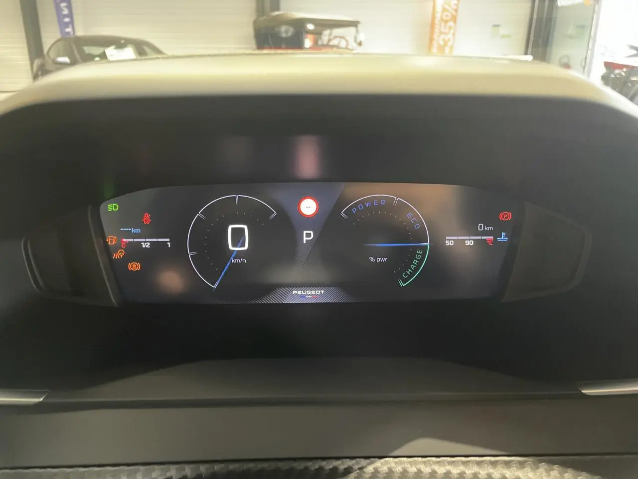 Tableau de bord numérique du Peugeot 2008 hybride affichant la vitesse, la puissance et les indicateurs de charge en vue frontale.