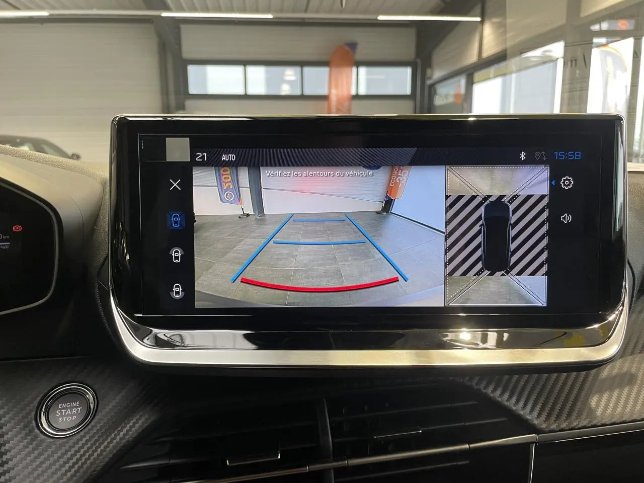 Écran tactile intérieur montrant la caméra de recul et la vue 360° du Peugeot 2008 hybride bleu, planche de bord carbone.