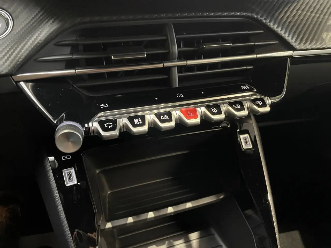 Détail de la console centrale noire brillante du Peugeot 2008 Hybrid 2026 avec boutons de commande et prises USB.