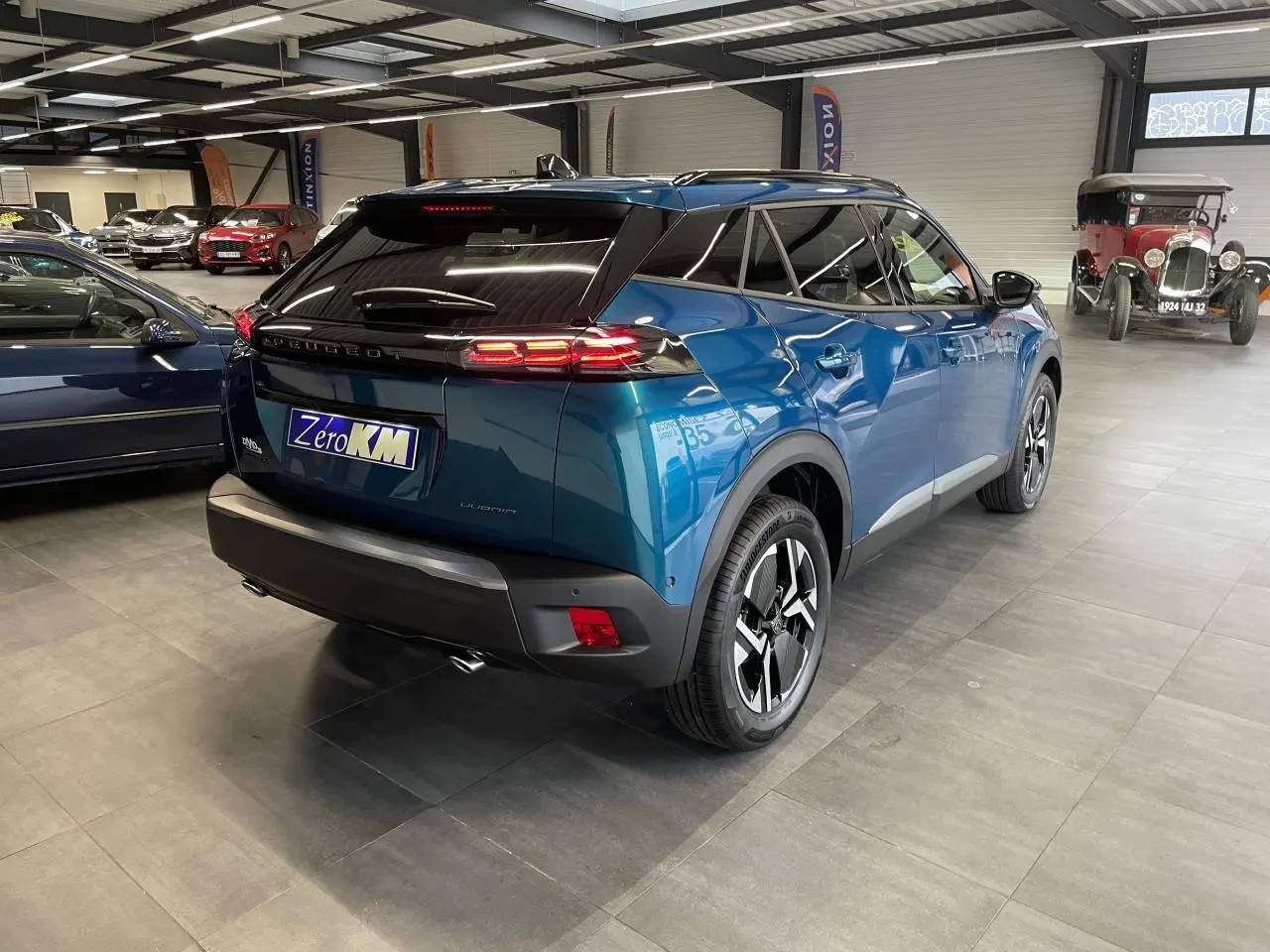 Vue 3/4 arrière droite d’un Peugeot 2008 bleu métallisé avec feux arrière à LED et jantes alliage 17 pouces.