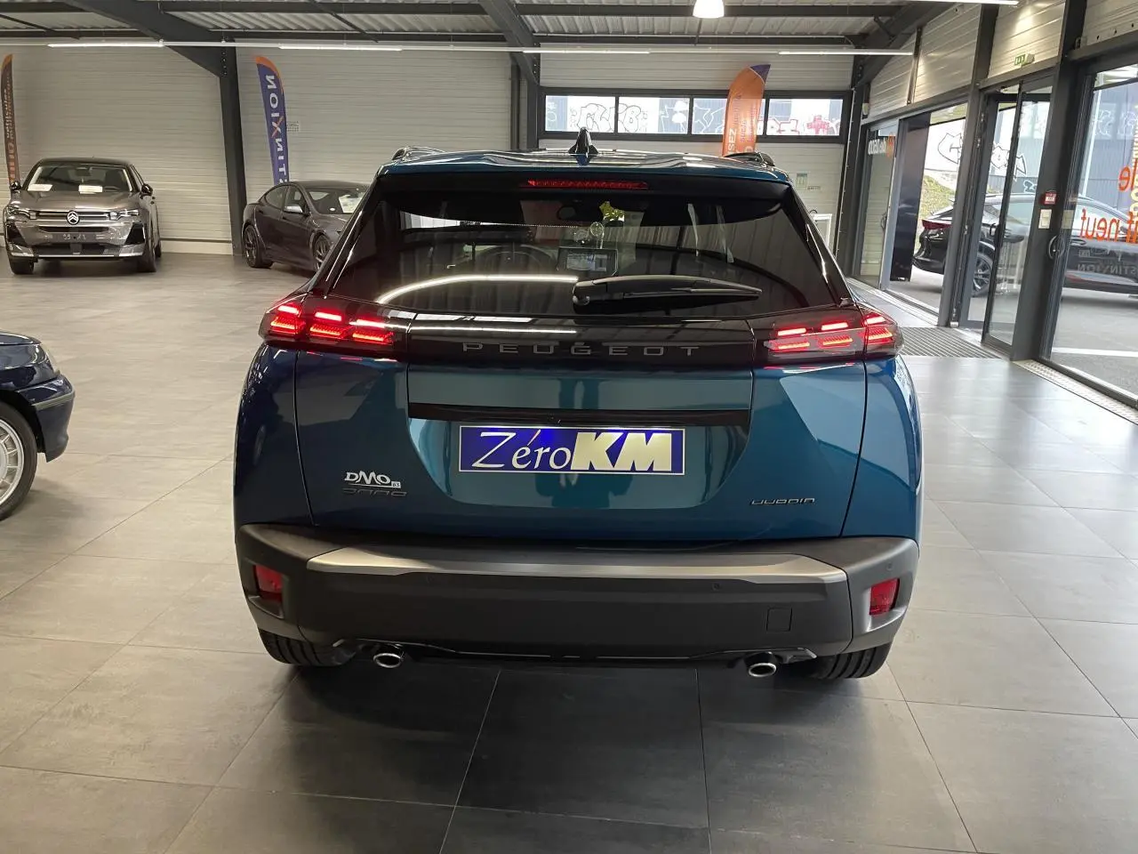 Vue arrière d'un Peugeot 2008 bleu avec feux arrière LED 3 griffes et double sortie d'échappement chromée.