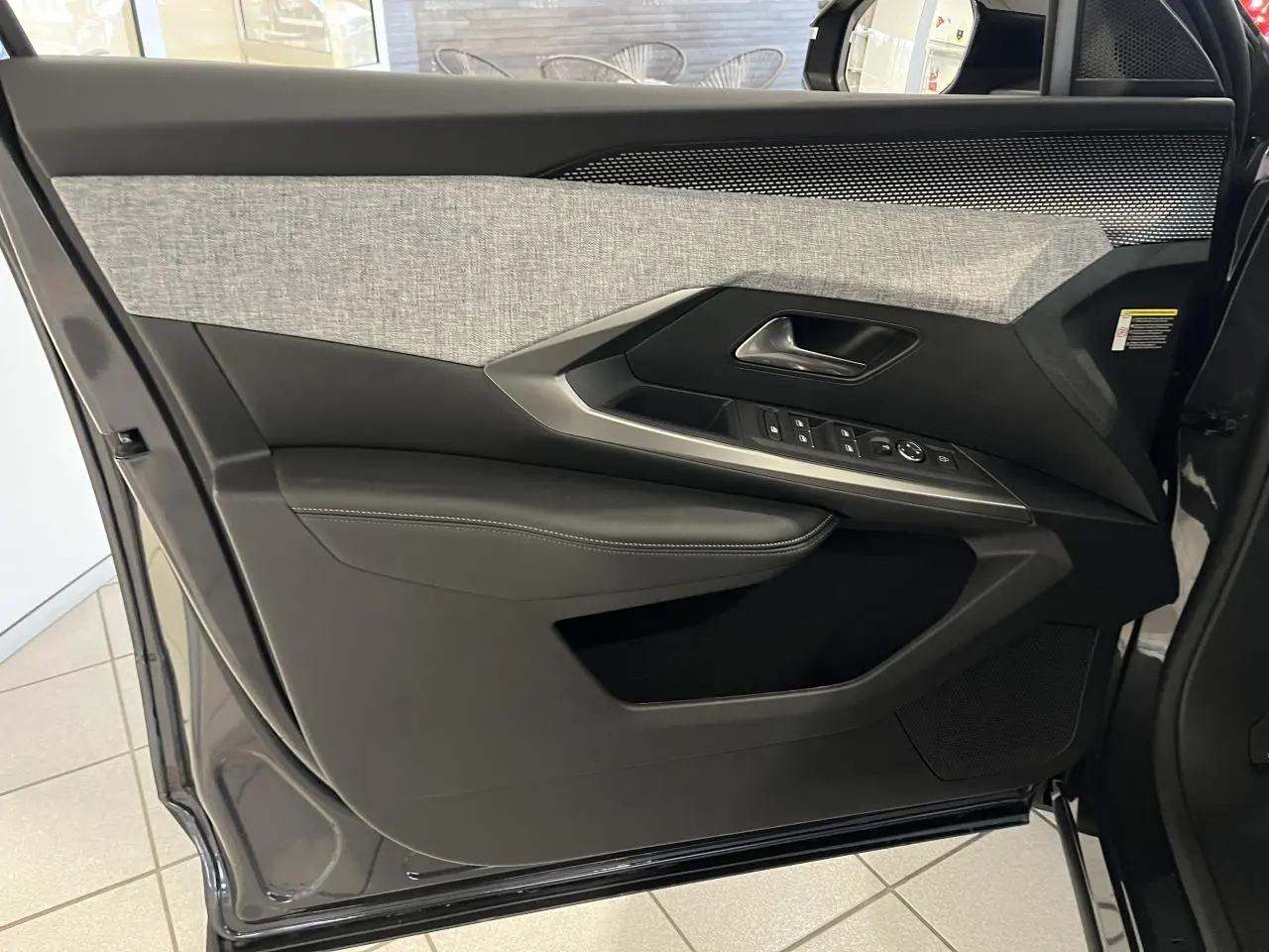 Porte intérieure côté gauche du Peugeot 3008 gris titanium, avec garniture tissu chiné et commandes de vitres intégrées.