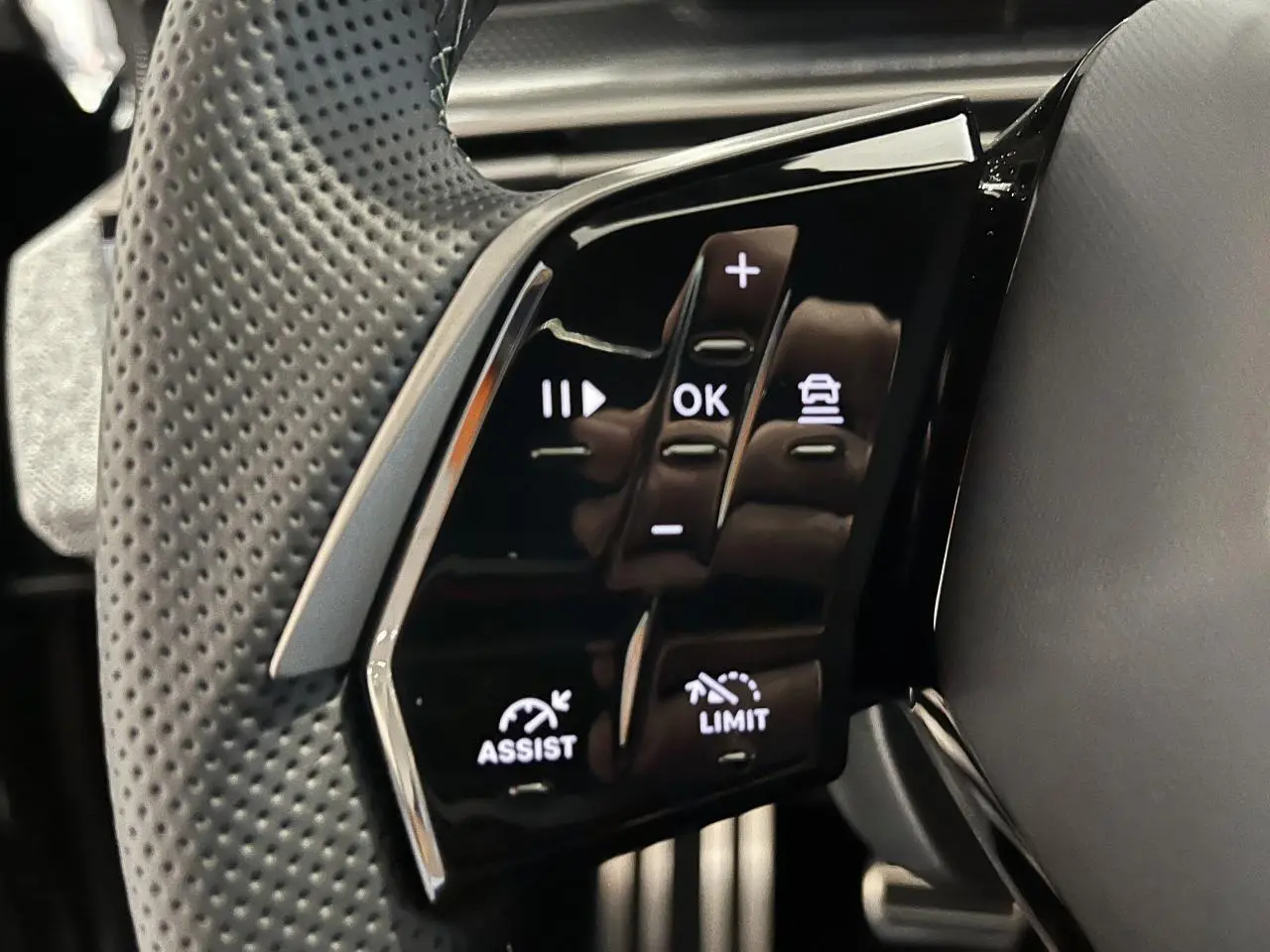 Gros plan sur les commandes noires du volant perforé du Peugeot 3008 gris titanium version GT hybride.