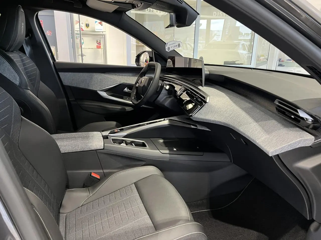 Intérieur côté conducteur du Peugeot 3008 gris titanium 2025, avec tableau de bord tissu Rimini et écran panoramique.