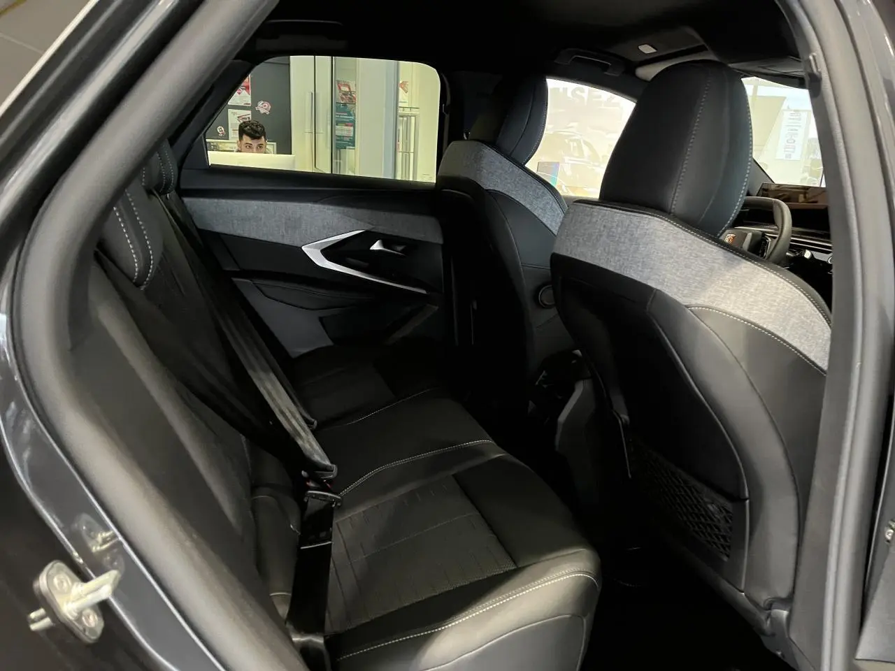 Vue intérieure côté gauche des sièges arrière en cuir noir et tissu gris du Peugeot 3008 GT gris titanium 2025.