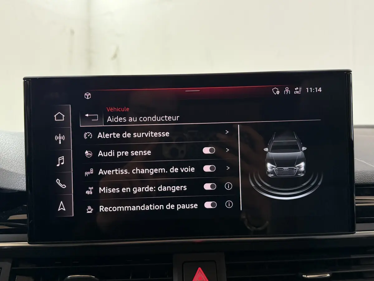 Écran tactile central affichant les aides au conducteur avec une vue avant stylisée d’une Audi A4 gris foncé.