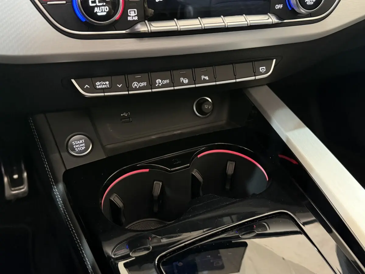 Gros plan intérieur sur la console centrale noire de l’Audi A4 gris foncé, avec boutons de commande et bouton démarrage visible.