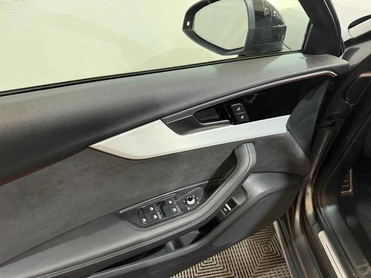 Vue intérieure côté conducteur de la porte gris foncé de l'Audi A4 35 TFSI avec commandes électriques et garniture cuir et alcantara.