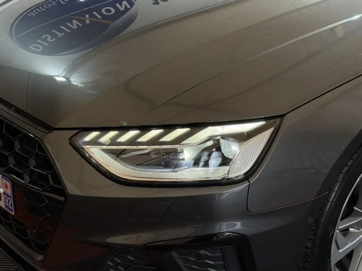 Gros plan sur le phare avant droit et la calandre d’une Audi A4 gris foncé 35 TFSI 2022, détails LED visibles.