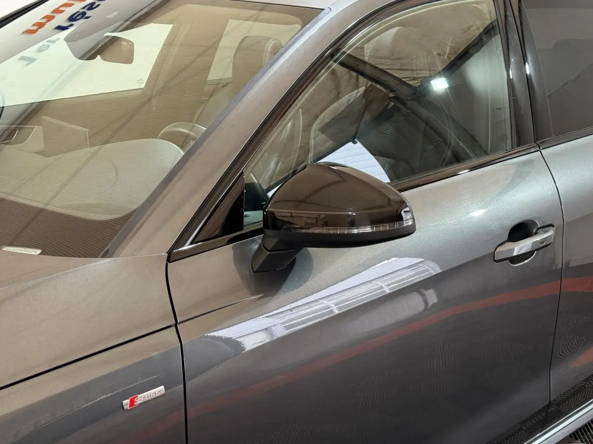 Vue rapprochée du côté gauche d’une Audi A4 gris foncé avec rétroviseur noir et badge S line visible sur la portière.