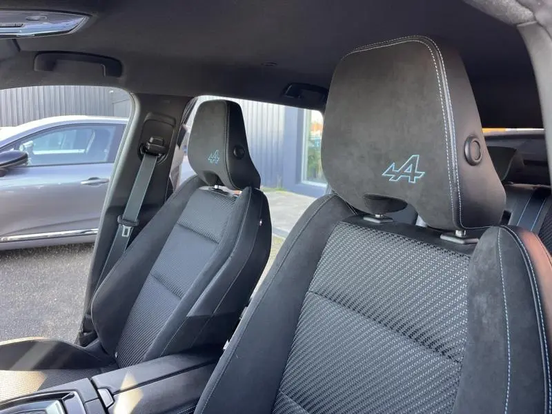 Vue intérieure des sièges avant du Renault Austral noir étoilé avec logo Alpine bleu sur les appuie-têtes.