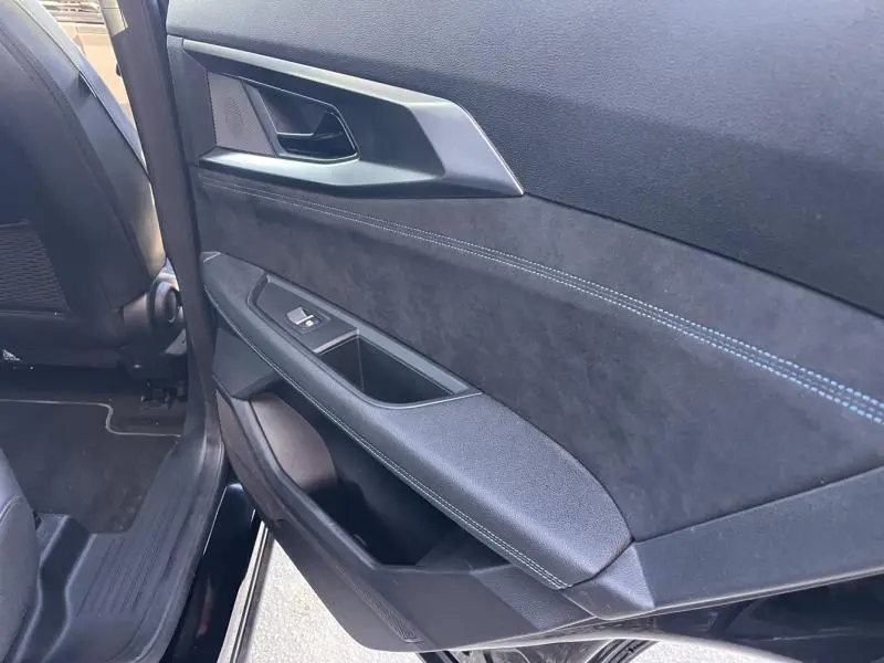 Vue intérieure côté gauche de la porte arrière noire étoilé du Renault Austral 2023 avec finition alcantara et surpiqûres bleues.