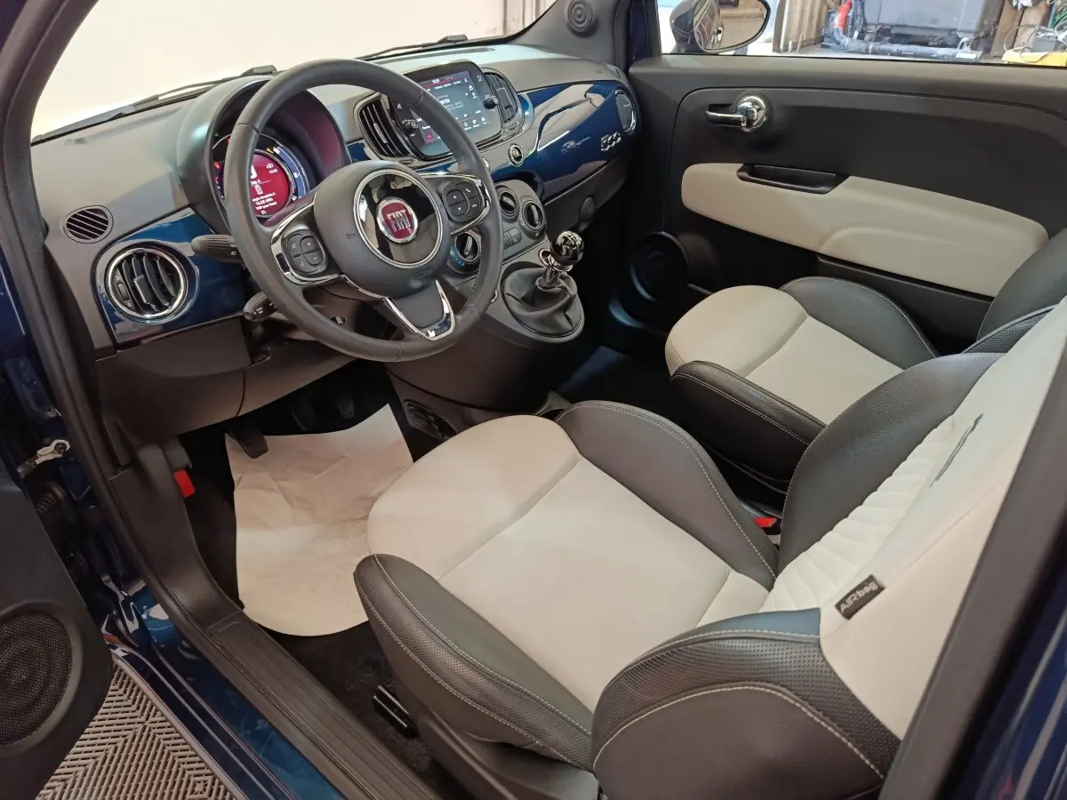 Vue intérieure côté conducteur de la Fiat 500 Dolcevita 2022, tableau de bord bleu et sièges bicolores cuir noir et beige.
