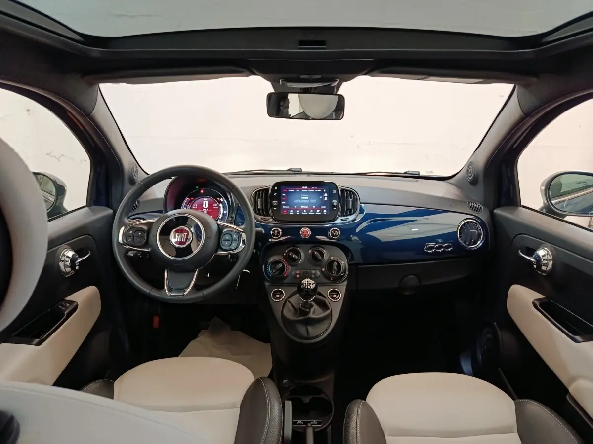 Vue intérieure avant de la FIAT 500 Hybrid 2022, tableau de bord bleu brillant avec écran tactile central et volant multifonctions.