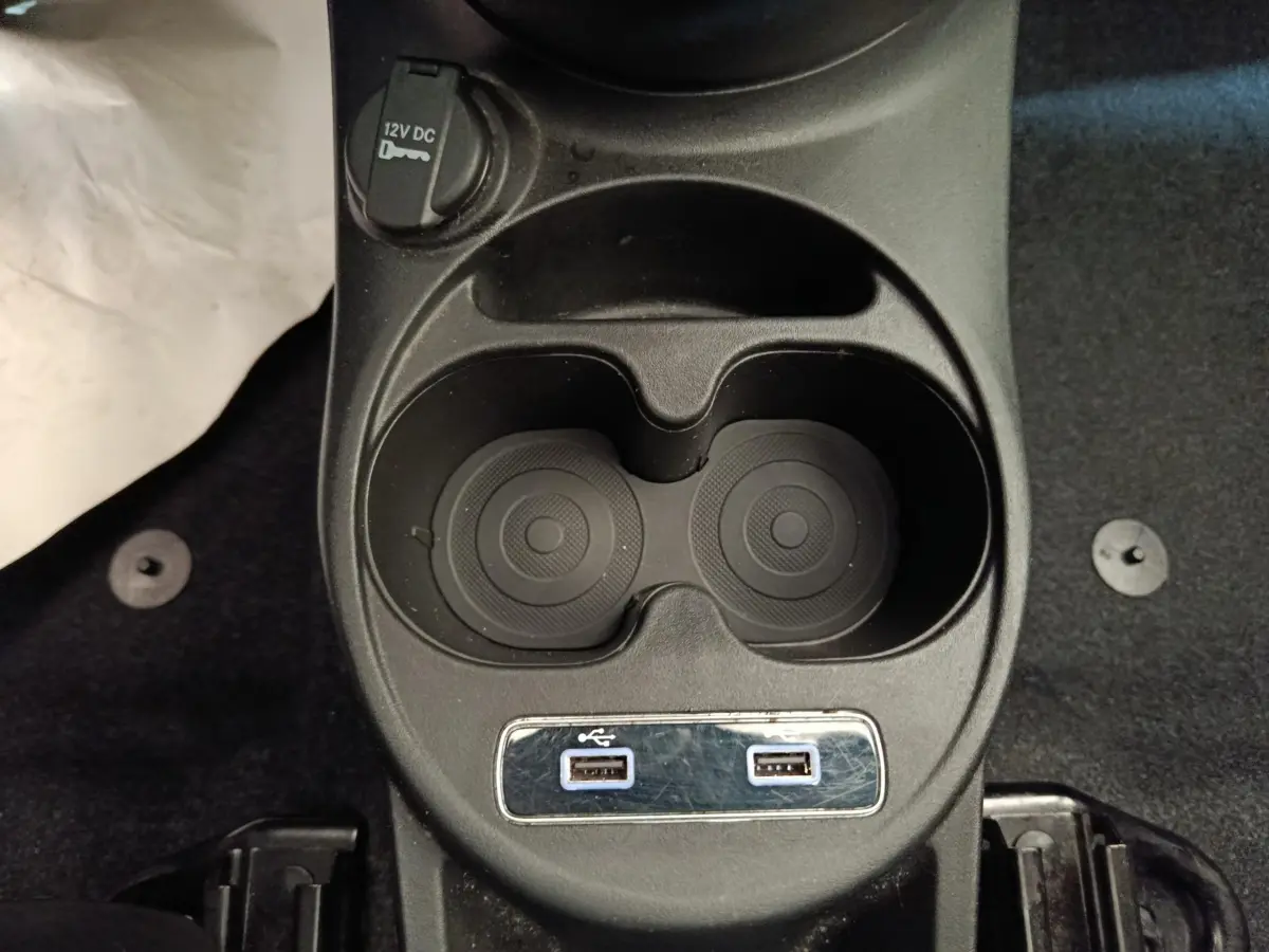 Vue rapprochée de la console centrale noire de la FIAT 500 Hybrid avec porte-gobelets et deux ports USB.